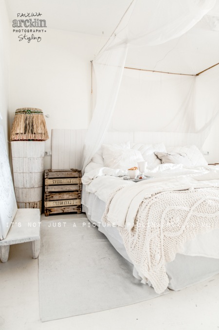Drewniane skrzynki i  łóżko z drewnianą ramą i bladachimem w białym kolorze