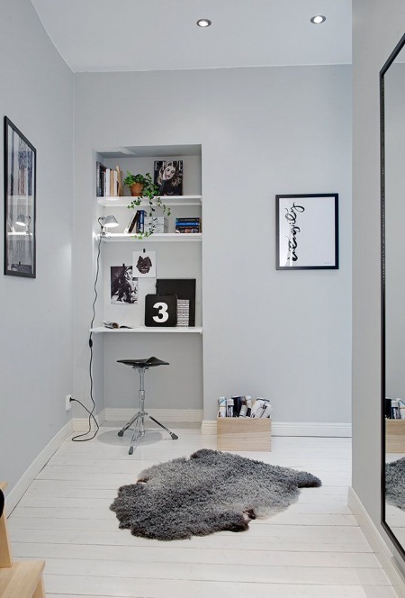 Szare ściany ,wnęka z półkami w przedpokoju w roli domowgo biura,nowoczesne grafiki na scianach,białe malowane deski na podłodze