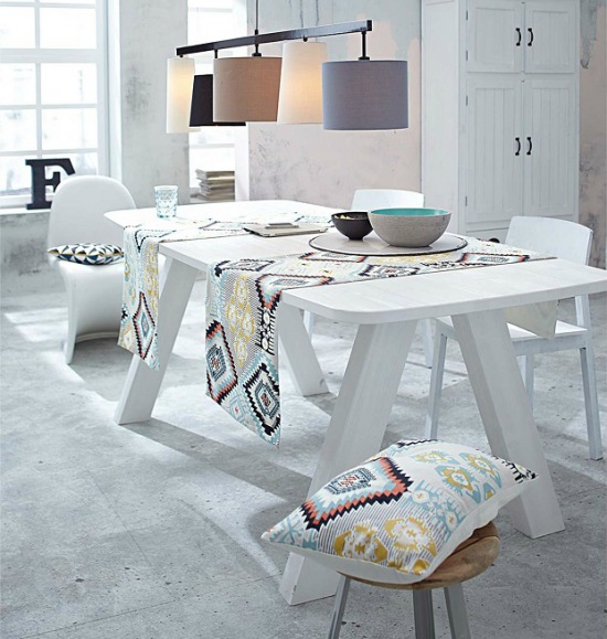 Biały duży stół z drewna na kozłach,białe krzesła i etniczne kolorowe bieżniki i poduszki w jadalni