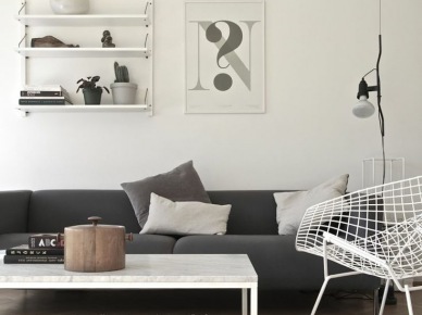 Szara nowoczesna sofa,biały stolik,biały metalowy fotel z azurami i grafiki z pólkami na ścianach (24883)