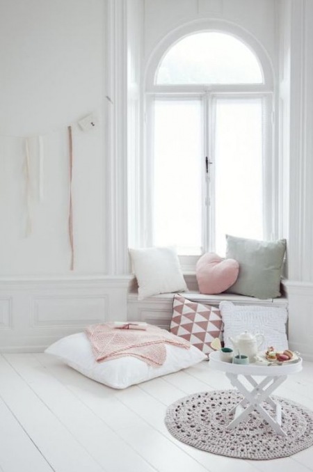 Biały salon z dekoracyjną lamperią i ozdobnymi pastelowymi poduszkami