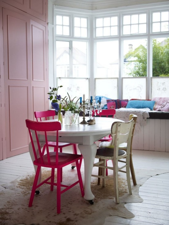 Różowe meble i krzesła przy białym okrągłym stole na kółkach