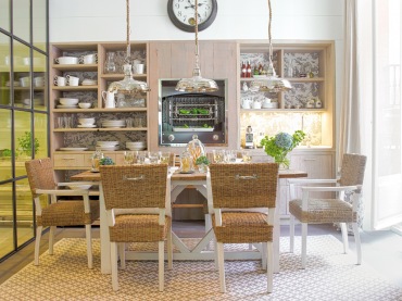 Biały tradycyjny stół z drewnianym blatem,drewniane krzesła z plecionymi siedziskami i oparciami,chromoniklowane rustykalne lampy wiszące,otwarte półki i przeszklona ściana w dużej kuchni (26418)