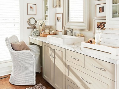 Biała łazienka w tradycyjnej aranżacji z wiklinowym fotelem,drewnianym lustrem,drewnianą podłogą z desek i zabudową szafek z umywalką naszafkową (26167)
