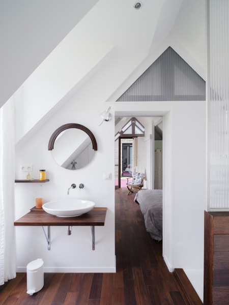 Biała łazienka z brązową ciemną podłogą , blatem pod umywalką i delami na ścianie