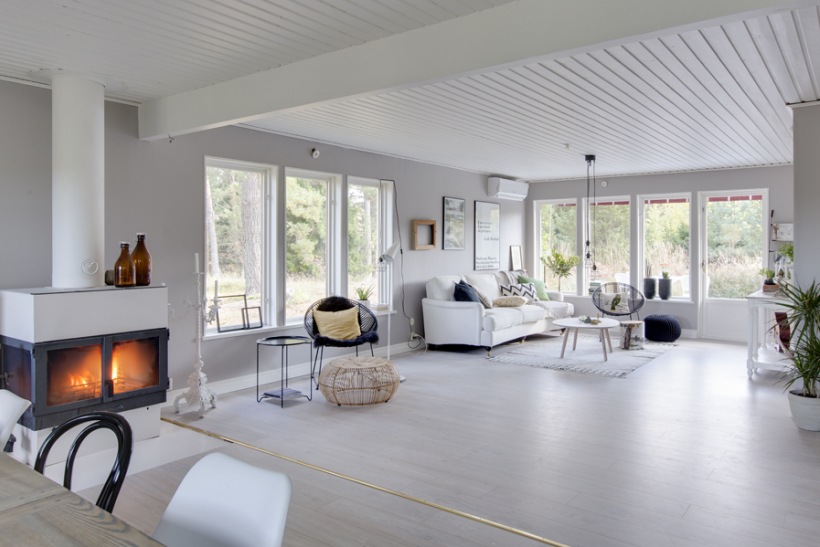 Otwarty duży biały salon w wiejskim domku w stylu skandynawskim