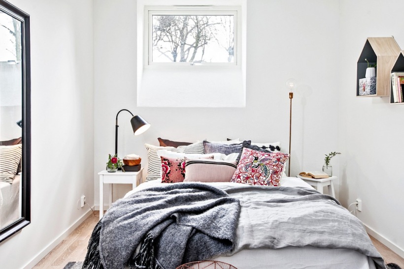 Prostokątne czarne lustro na ścianie w białej sypialni z różowymi poduszkami