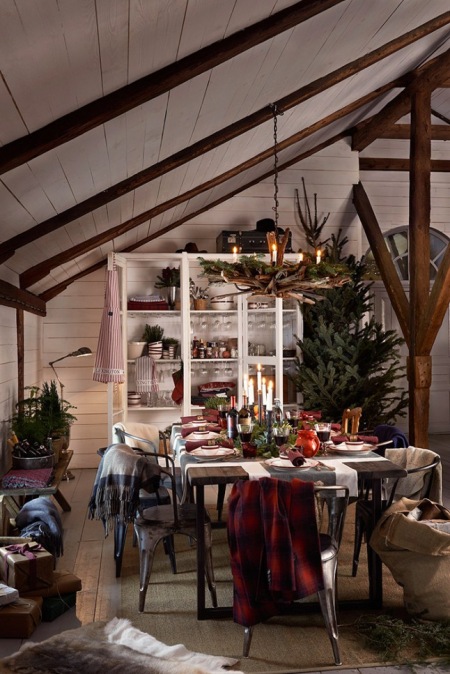 Tradycyjna świąteczna dekoracja wiejskiego stołu,rustykalny żyrandol z drewnianych gałązek z zielonym igliwiem i świeczkami,biały kredens w wiejskim stylu,drewniane belki,metalowe krzesła tolix w jadalni w rusttykalnym stylu