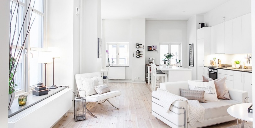 Biała sofa z fotelem w nowoczesnym i otwartym salonie skandynawskim