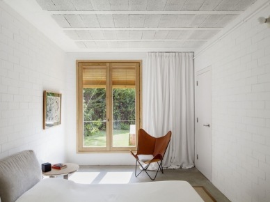 Ściany z białej cegły i fotel butterfly ze skóry w białej sypialni skandynawskiej (22905)