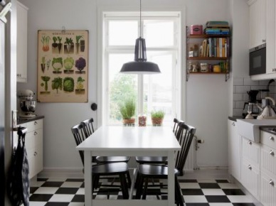 Biało-czarna terakota ułożona w karo w białej kuchni z białym stołem, czarnymi krzeslami i plakatem z ziołami (24527)