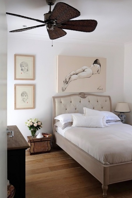 Stylowe pikowane łóżko i ilustracje w aranzacji biało-beżowej sypialni