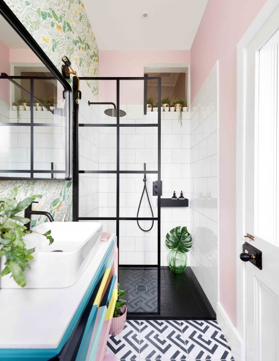 Kolorowa aranżacja łazienki z różową ścianą i czarnym prysznicem