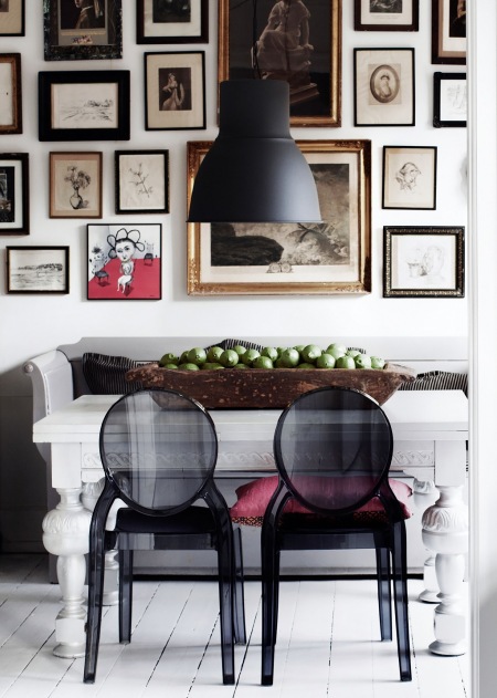 Czarna lampa pendant,galeria fotografii i grafik w różnych stylach na białej ścianie nad drewnianą ławką