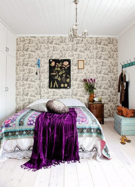 Wzorzysta tapeta, obrazy z motywem roślinnym i turkusowo-fioletowe detale w sypialni