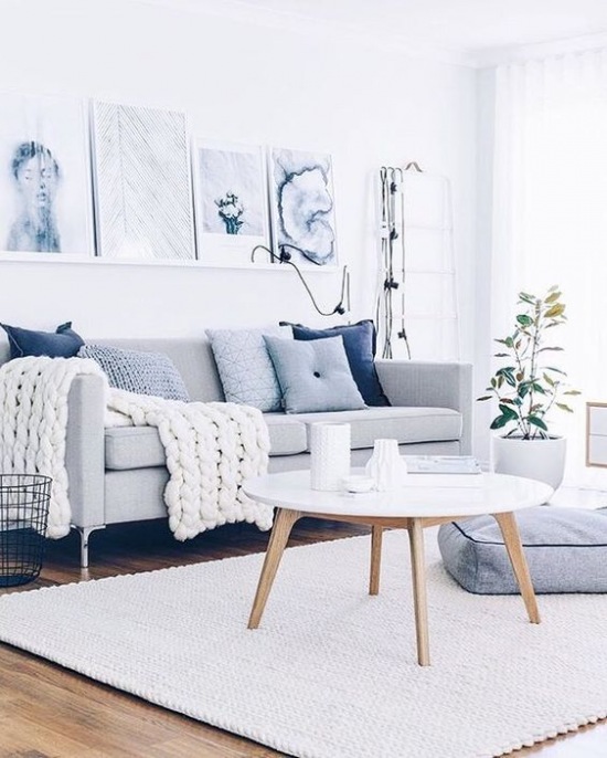 Szara sofa w białym salonie w stylu skandynawskim