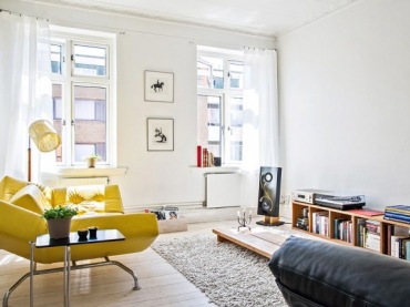 Żółta nowoczesna sofa w białym salonie skandynawskim z niskim stolikiem i pólkami  z drewna (25683)