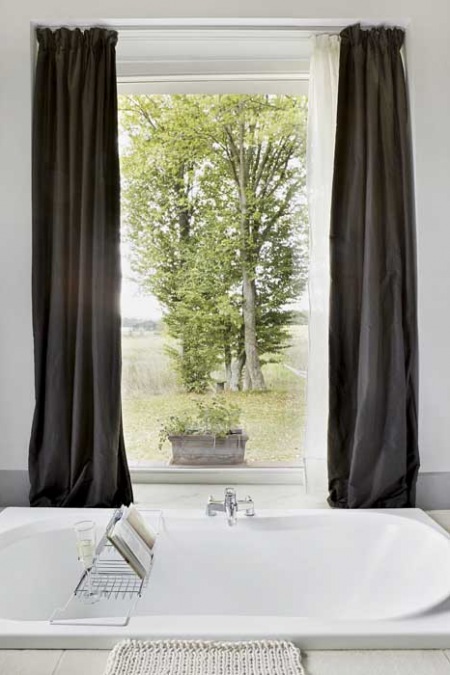 Biała łazienka  z dużym oknem z szarymi zasłonami