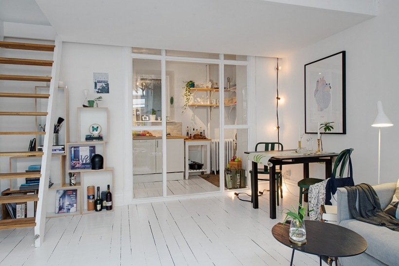 Otwarta przestrzeń jednopokojowego mieszkania  z kuchnią a szklaną ścianką