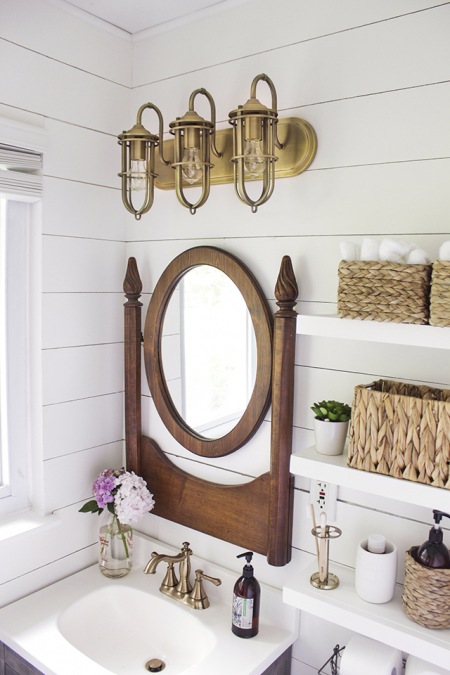 Złote lampy i drewniane lustro w aranżacji łazienki