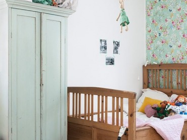 Drewniane łóżko oraz pomalowana miętową farbą szafa wprowadzają naturalny charakter do pokoju dziecięcego. Kwiatowy...