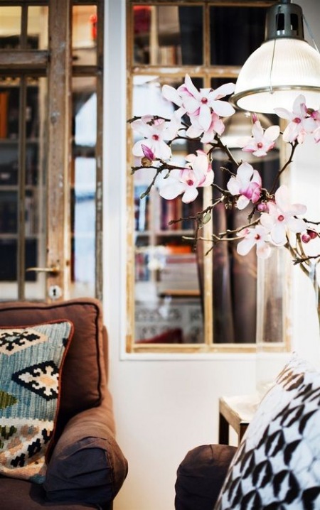 Brązowa kanapa  w salonie udekorowana kwiatem
