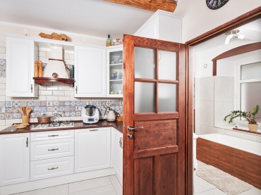 Drzwi z ciemnego drewna oraz inne naturalne dodatki wnoszą do kuchni przyjemny ciepły charakter. W połączeniu z bielą...