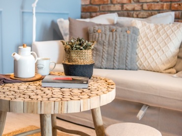 Warto zwrócić uwagę na okrągły stolik kawowy, który stoi w salonie. Ma drewniane nóżki o nieco nieregularnym kształcie...