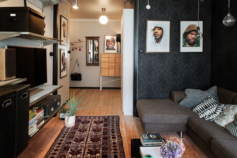 Szara sofa,czarna tapeta i etniczny dywan w salonie