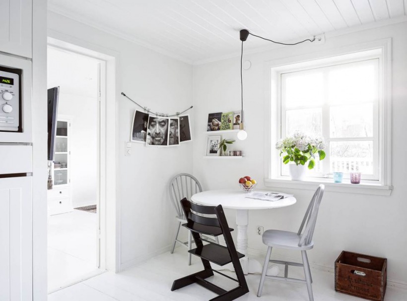Biały stół w kuchni skandynawskiej,okrągły biały stgół w kuchni,czarne krzesła z drewna w stylu skandynawskim,jadalnia w stylu skandynawskim,biało-czarna jadalnia skandynawska,biała kuchnia w stylu skandynawskim,skandynawska kuchnia,biała