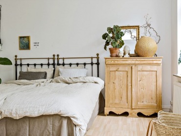 W sypialni na eleganckiej i zdobionej komodzie z drewna stworzono kompozycję z ozdobnych elementów. Są tu kwiaty, a...