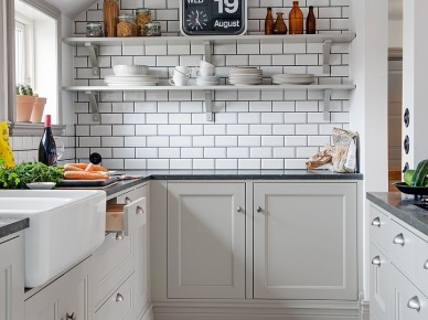Biała glazurowana płytka cegielka z czarna spoiną na ścianie w szarej kuchni z czarnymi blatami i białą podłogą z desek (25944)