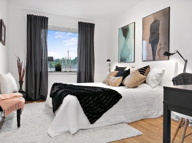 Nowoczesne artystyczne fotografie na ścianie w białej sypialni z czarnymi zasłonami,biurkiem i futrzaną narzutą (27519)