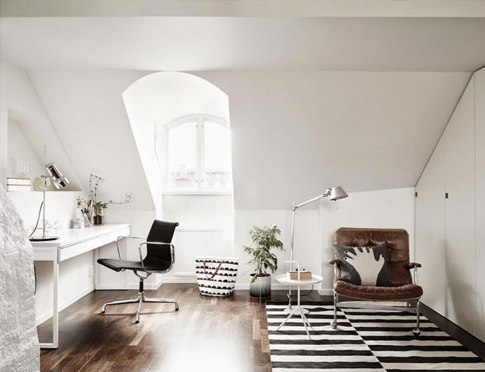 Biało-czarny dywan w paski,skórzany nowoczesny fotel,białe nowoczesne biurko-konsolka,skandynawska torba i srebrna lampa stojąca