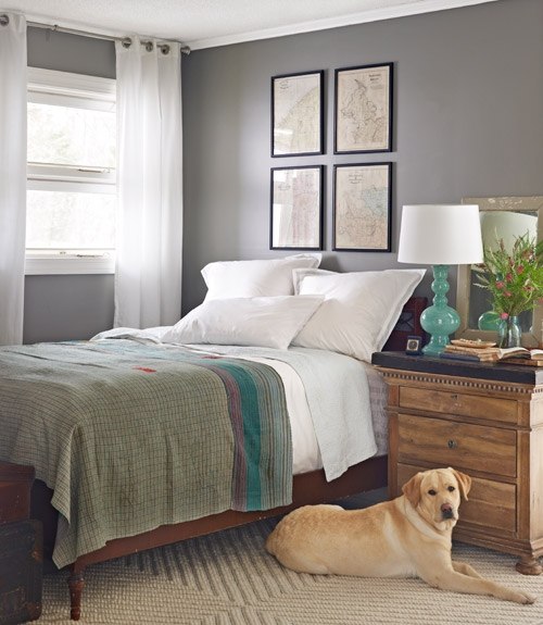 Turkusowa ceramiczna lampa w sypialni z drewnianym łóżkiem,komodą i szarymi ścianami