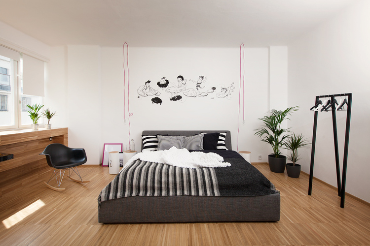 Nowoczesna sypialnia z tapicerowanym łóżkiem, grafikami na ścianie w czarno-białych kolorach