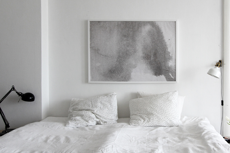 Czarna lampka biurkowa i biały kinkiet przy łóżku w minimalistycznej sypialni