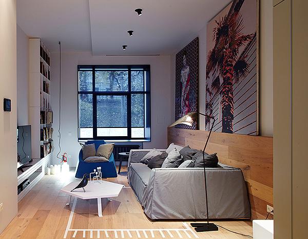 Nowoczesny salon z szarą sofą,dużymi fotografiami, pomysłową podłogą i okładziną ścienną z drewna