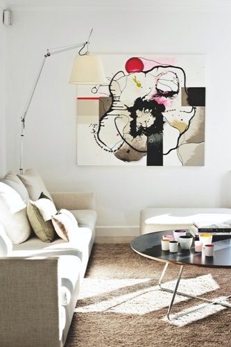 Lampa podłogowa z wysiegnikiem, okrągły stolik i piękny obraz w salonie