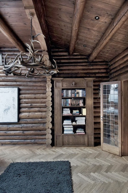 Aranżacja salonu z biblioteczką w domu z drewnianych bali