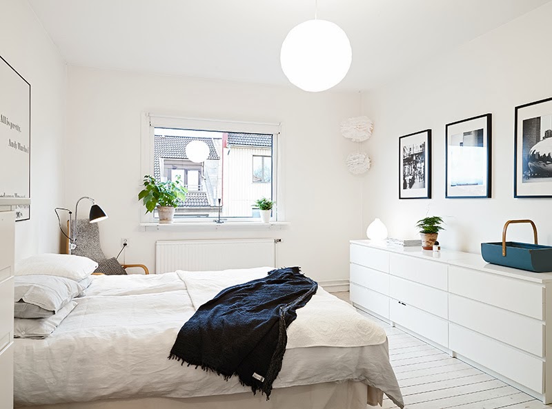 Białe komody z szufladami i biało-czarne grafiki w skandynawskiej sypialni