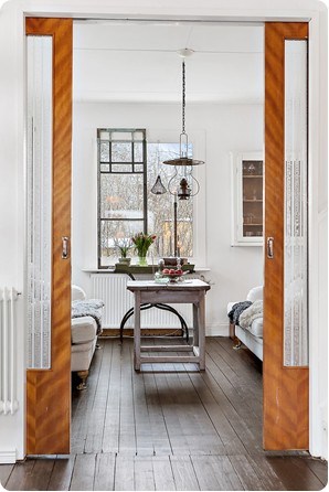 Miodowe drewniane drzwi przesuwne w jadalni ze stołem vintage i rustykalną lampą z metalu i szkła