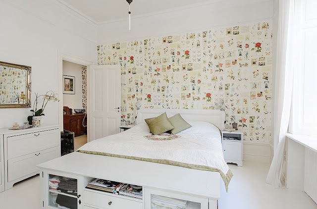 Biała sypialnia z roślinną tapetą nad łóżkiem