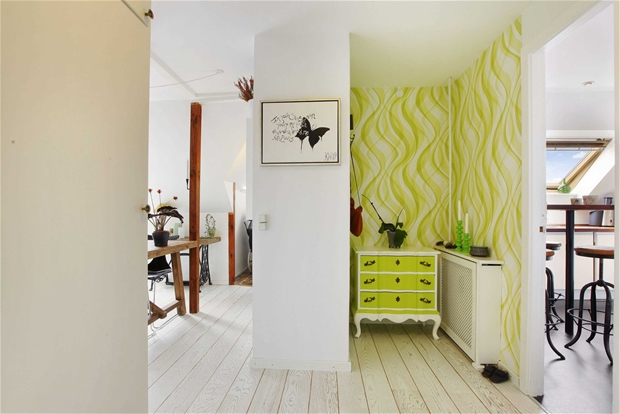 Drewniane słupy,grafiki i limonkowa komoda z tapetą na ścianie