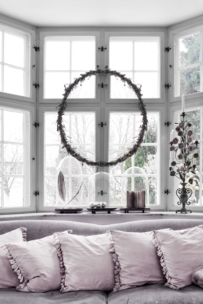 Naturalny wianek świąteczny na oknie przy kanapie z bialymi poduszkami