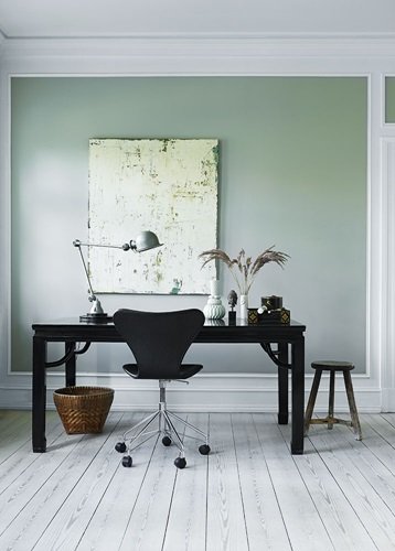 Miętowa ściana w pokoju z czarnym biurkiem i białą podłogą z desek