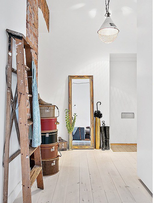 Bielone deski,drewniana drabina,okragłe ozdobne pudła,industrialna lampa i drewniane prostokątne lustro podłogowe