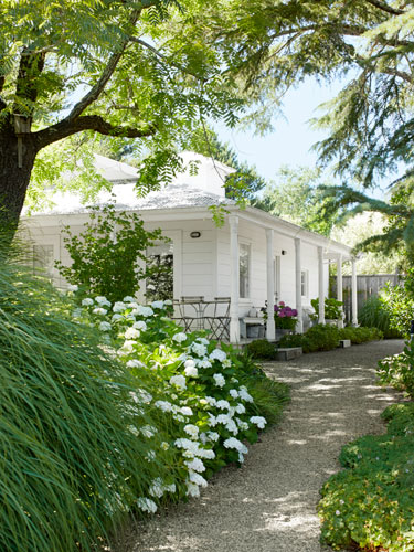 Biały domek z ogrodem pełnym bylin i hortensji