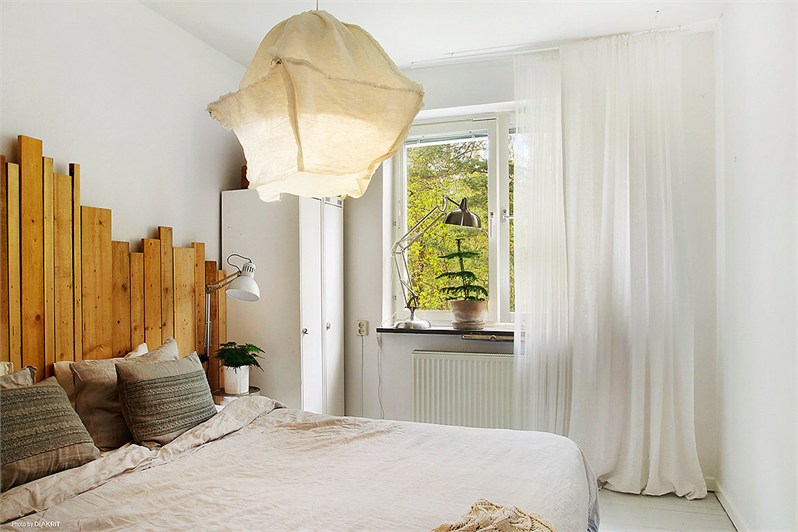 Wezgłowie z desek z recyklingu, lampa na drucianym stelażu , białe ściany i meble w sypialni