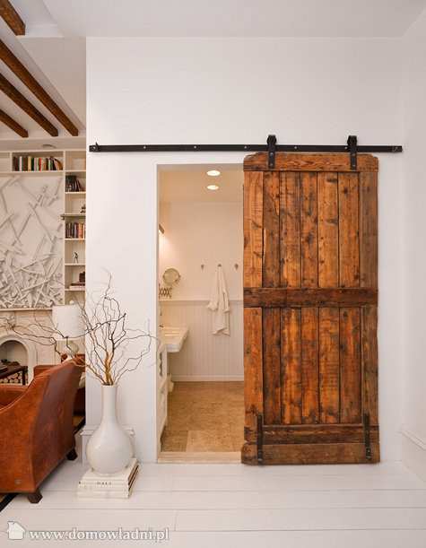 Wiejskie drzwi drewniane przesuwne na żeliwnej szynie na ścianie do łazienki